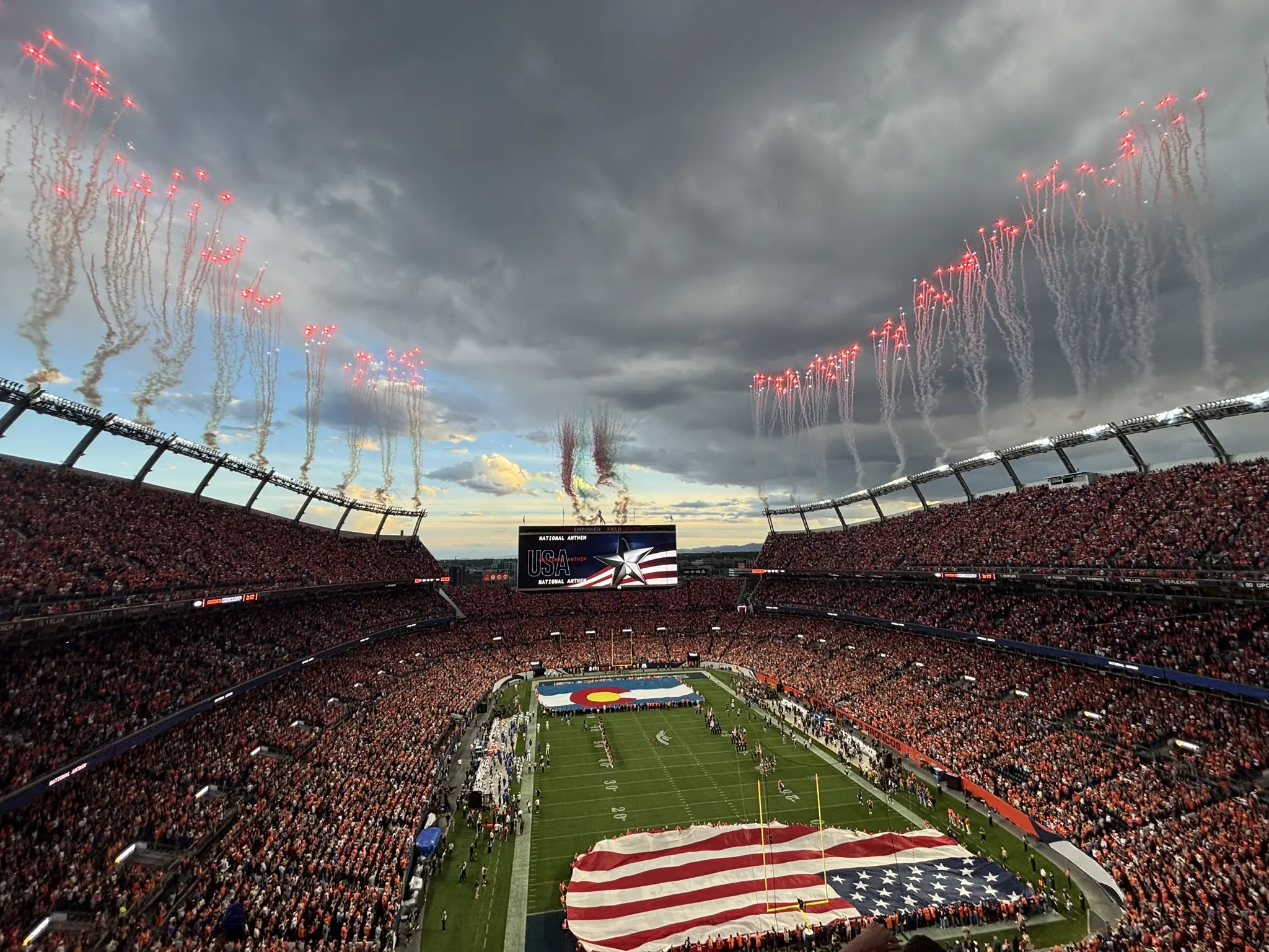 Pregame fireworks and a giant flag over a full Empower Field at Mile High