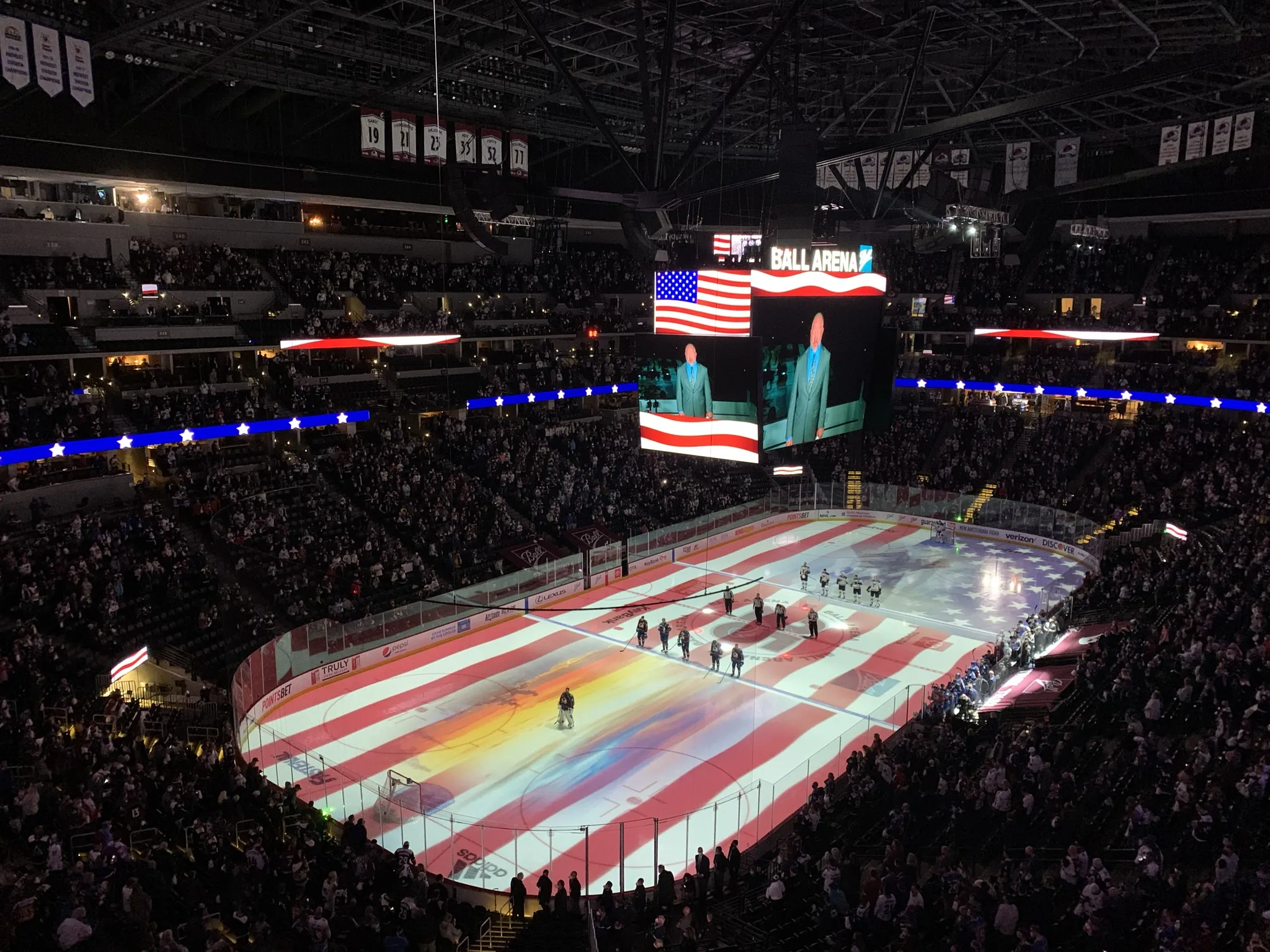An American flag projected on the ice at Ball Arena during the anthem